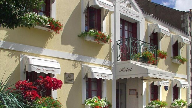 A hotel with a classic facade, featuring multiple windows with flower boxes and awnings labeled "La Cognette." - Hotel la Cognette (Issoudun)