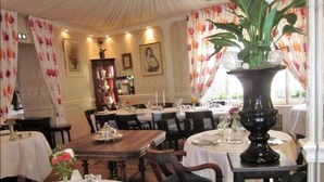 A dining area with wooden tables, white tablecloths, and floral decorations. - Hotel la Cognette (Issoudun)