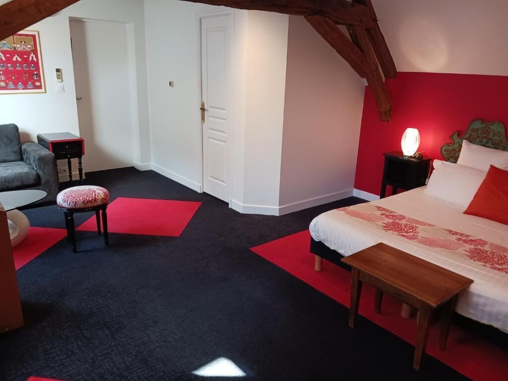 Un dormitorio con cama, mesita de noche, lámpara y una silla.