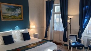 A hotel room with a bed, a chair, a desk, a lamp, and a painting on the wall. - Hotel la Cognette (Issoudun)
