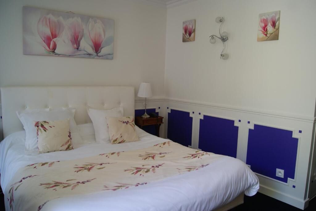 Ein Schlafzimmer mit einem großen Bett, weißer Bettwäsche und floralen Bildern an den Wänden.