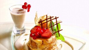 A dessert with strawberries and chocolate on a plate, accompanied by a glass of a creamy beverage. - Hotel la Cognette (Issoudun)