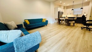 Ein modernes Wohnzimmer mit einer Couch, einem Couchtisch und einem Essbereich mit Tisch und Stühlen.