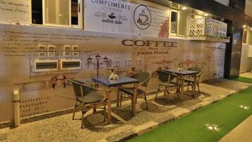 An outdoor seating area with tables and chairs, a green artificial turf path, and a wall with text and graphics.