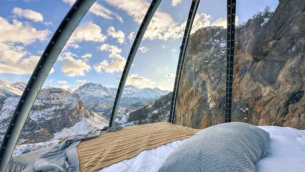 A bed with a view of snow-covered mountains and a rocky cliff. - OVO Patagonia (El Chalten)