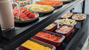 Un bufé con diferentes opciones de comida, como frutas, verduras y platos ya preparados.