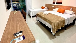 Habitación de hotel con dos camas, un escritorio, un televisor y una ventana con cortinas.