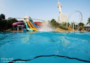 Parque acuático con una piscina grande, toboganes de agua y una estructura de torre al fondo.