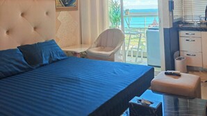 Un dormitorio con cama, una silla, un escritorio y vista al mar.