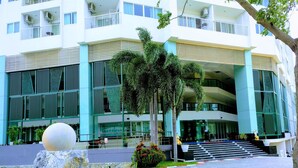 Un edificio moderno con varios pisos, amplias ventanas y una escalera central que conduce a la entrada.