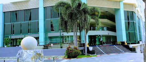 A modern building with multiple floors, large windows, and a central staircase leading to the entrance.