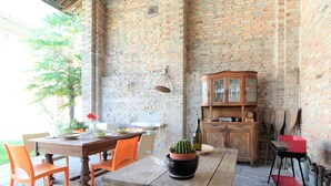 Ein rustikaler Essbereich mit Backsteinwand, Holztisch und orangefarbenen Stühlen.