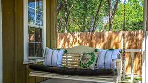 Un porche de madera con un banco, una ventana y una cerca de madera al fondo.