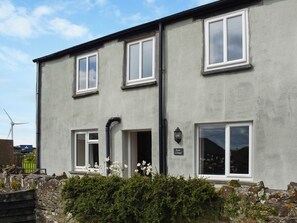 A two-story building with multiple windows, a visible nameplate, and a stone wall with vegetation. - UK47757 - Rose Cottage (Launceston)