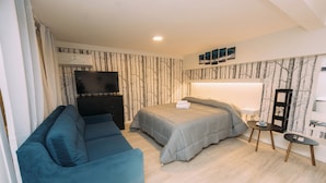 Ein modernes Schlafzimmer mit Bett, Sofa, Fernseher und Nachttisch.