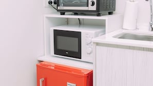 Eine kleine Küchenzeile mit einer Mikrowelle, einem Toaster und einem kleinen Kühlschrank.
