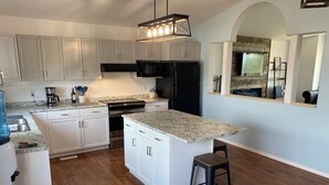 A modern kitchen with white cabinets, a black refrigerator, a built-in oven, and a granite countertop.