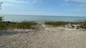 A gravel path leading to a body of water with a clear sky above.