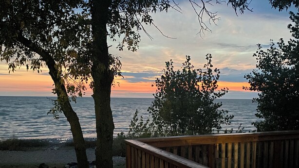 A wooden deck overlooking a body of water with trees framing the view.