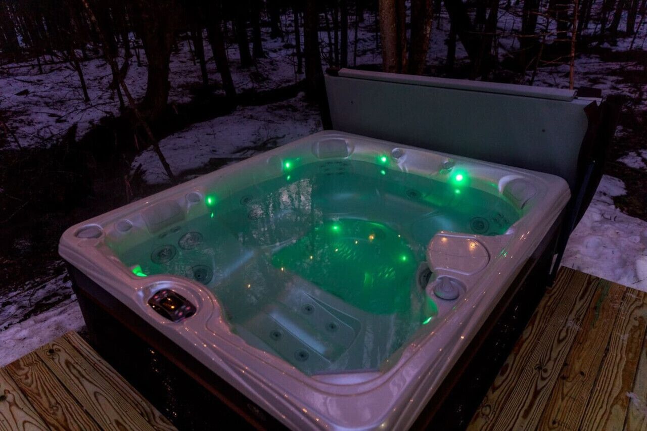 Een bubbelbad met groene verlichting in een besneeuwde omgeving.