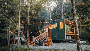 Una cabaña en un bosque con terraza y zona de estar al aire libre.