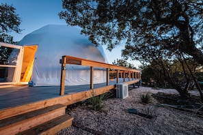 A modern, dome-shaped building with a wooden deck and a sign that reads "Harmony." - Astryia Glamping (Fredericksburg)