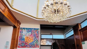 A grand interior with a large chandelier, a staircase, and a colorful mural. - SUITES DEL JARDIN PRINCIPAL (Guanajuato)