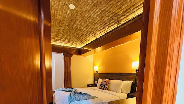 A bedroom with a bed, bedside tables, a nightstand, and a ceiling with a textured pattern. - SUITES DEL JARDIN PRINCIPAL (Guanajuato)