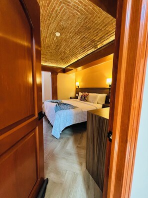 A bedroom with a bed, bedside tables, a nightstand, and a ceiling with a textured pattern. - SUITES DEL JARDIN PRINCIPAL (Guanajuato)