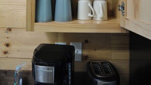 A wooden cabinet with shelves containing kitchen items like a coffee maker, cups, and a measuring cup. - Newly Refurbished 2 Bedroom Duplex cabin in Albany, KY with Slip, Wi-Fi #19 (Albany)