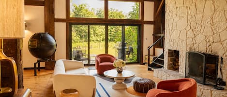 A spacious living room with a fireplace, large windows, and a stone wall.