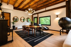 Una habitación con techo de madera, una mesa de comedor con sillas, un piano, un espejo grande y un globo terráqueo.