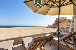 Eine Terrassenanlage am Strand mit Blick auf das Meer, ein Liegestuhl und ein Himmelbett.
