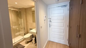 Un baño moderno con cabina de ducha de vidrio, inodoro y puerta blanca.