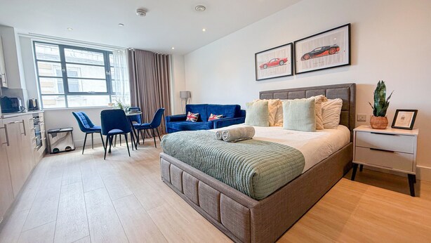 Una habitación de hotel moderna con una cama grande, un escritorio, un sofá azul y un área de comedor.
