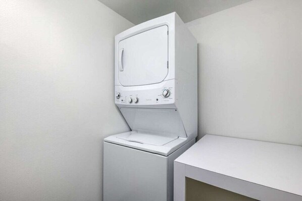 A laundry room with a washing machine and dryer stacked vertically.