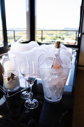 Ein Tisch mit einer Champagnerflasche, zwei Weingläsern und einer Kerze mit dem Aufdruck 'Dora'.