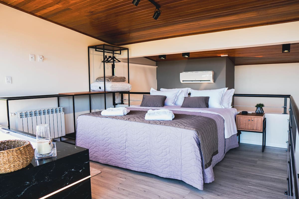 A modern bedroom with a bed, bedside tables, a radiator, and a hanging light fixture.