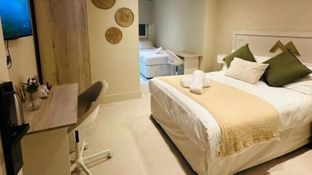 A bedroom with a bed, a desk, and a television. - MSM Arena Hotel (London)