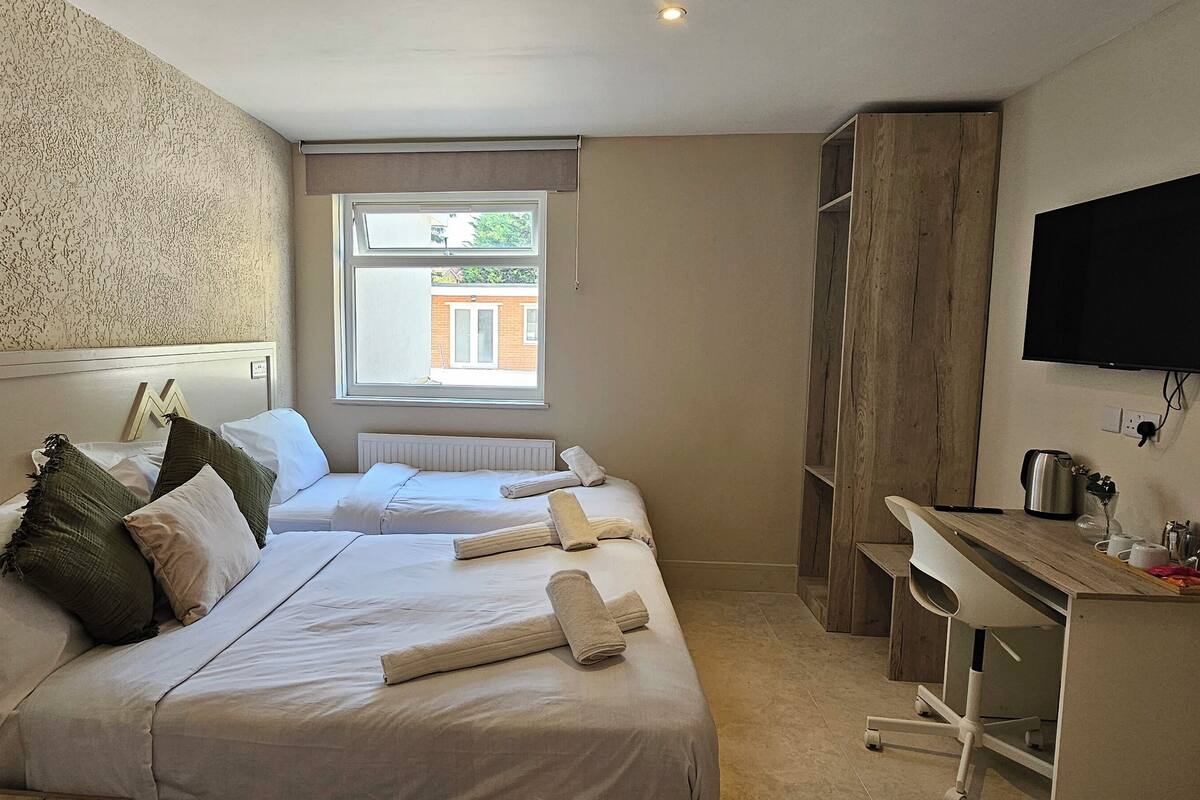 Hotellihuone, jossa on kaksi sänkyä, televisio, ikkuna, josta on näkymä, ja pieni keittotila.