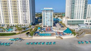Un hotel con varios edificios altos, una piscina y servicios frente a la playa.