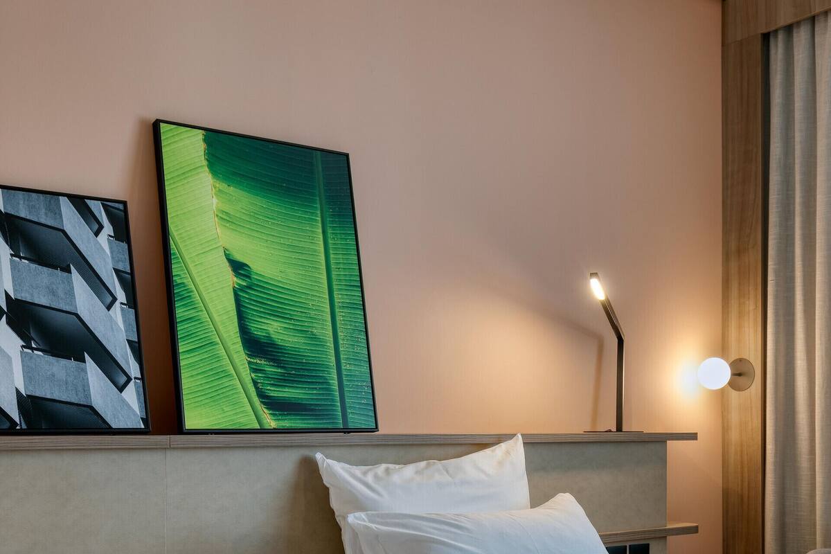 Une chambre d’hôtel avec deux lits, une table de chevet avec une lampe et des œuvres d’art accrochées au mur.