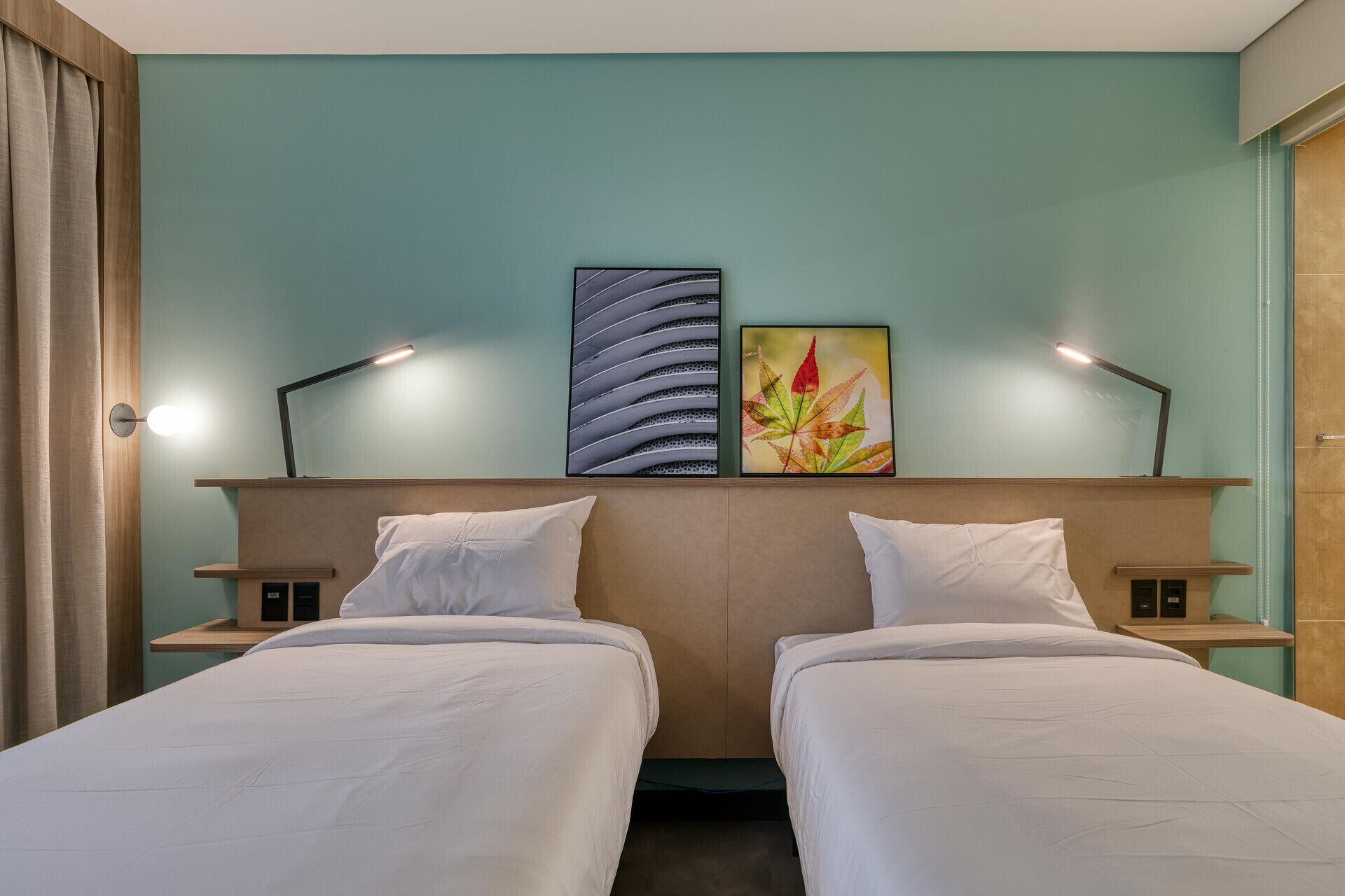 Habitación de hotel con dos camas, una obra de arte grande en la pared y lámparas de noche.