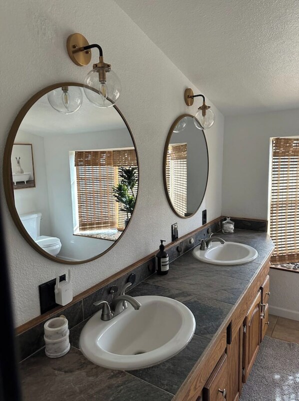 A bathroom with two sinks, a mirror, and a towel dispenser. - Step away from the noise of the city and into a country home get away (Springville)