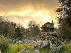 A house surrounded by rocks and trees with a cloudy sky. - Step away from the noise of the city and into a country home get away (Springville)