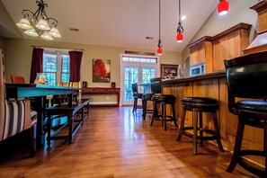 A spacious kitchen with wooden cabinets, a dining area with a bench, and a bar with stools. - Spacious 5-bedroom house in serene Sevierville with Pool and free WiFi (Sevierville)