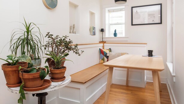 A room with a wooden bench, a table, potted plants, a clock, and a window with a view of the outside. - Best Denver Neighborhood! Walkable to EVERYTHING!  (Denver)