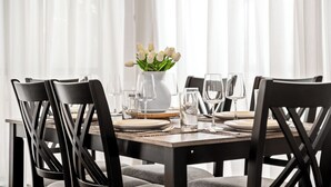 Et spisebord dækket med hvide tallerkener, klare glas og en vase med hvide tulipaner.