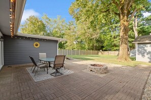 Une terrasse avec une table et des chaises, un foyer et un cadran solaire sur le mur.