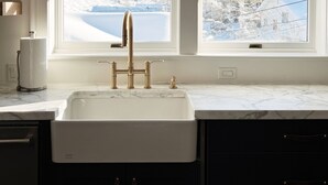 A kitchen with a white sink, two windows with snowy views, and pendant lights. - Charming Cottage steps to restaurants, shops & slopes (Park City)